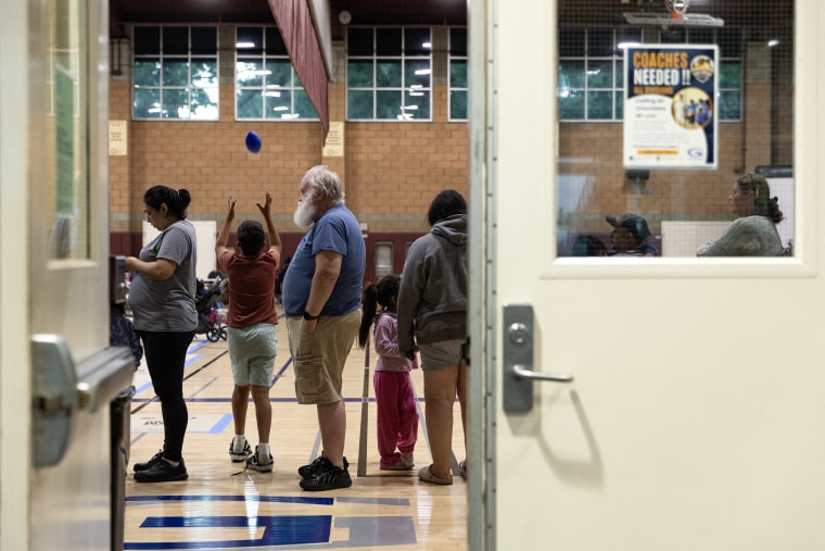 People stand in a line in a gymnasium.