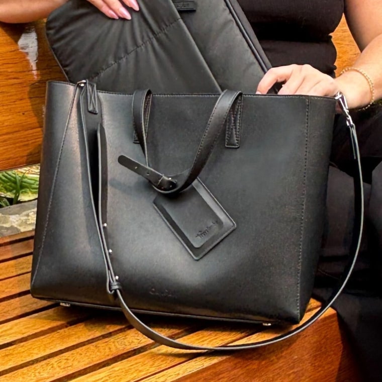 Woman sitting with the Haven Laptop Tote on her right side.